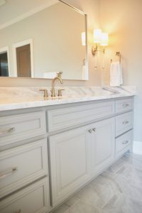 Bathroom with marble vanity, herringbone detail and sconces