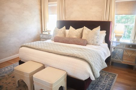 Bedroom with upholstered bed, bench ottomans and patterned area rug