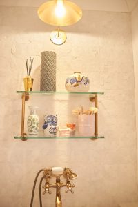 Styled brass bracket shelf vignette against patterned wallpaper