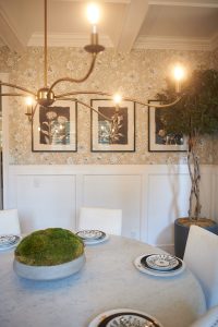 Dining room with botanical art, round table and moss centerpiece