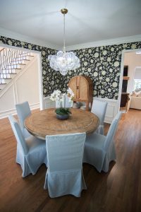 Dark floral wallpapered dining room with round table and drum chandelier