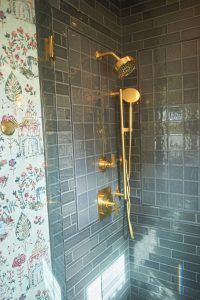 Emerald green tiled walk-in shower with brushed gold fixtures