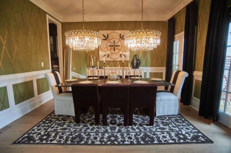 Formal dining room set with chargers beneath crystal chandeliers