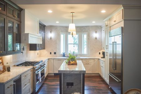 Kitchen with gray island, glass-front cabinets and pendant lights