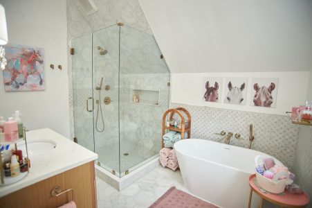 Children's bathroom with glass shower, freestanding tub and rattan stool