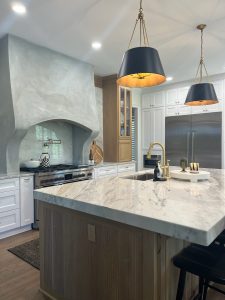 Kitchen with marble waterfall island, range and custom wood hood