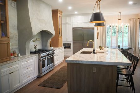 Kitchen with marble waterfall island, wood hood and bar stools