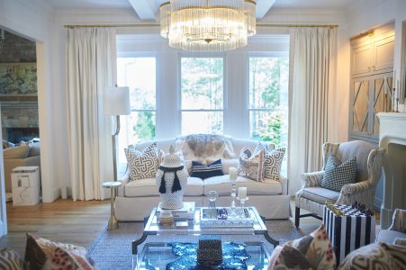 Bright neutral living room with chandelier and large windows