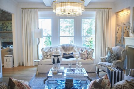 Neutral living room with glass coffee table, chandelier and bay window