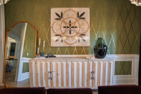 Olive harlequin accent wall with framed art and skirted console buffet