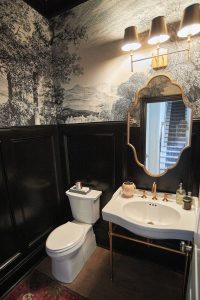 Dramatic powder room with black walls, scenic mural wallpaper and gold mirror