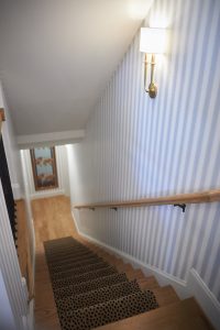 Striped wallpaper staircase landing with patterned stair runner