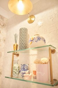 Styled glass shelf with brass bracket against a plaster wall