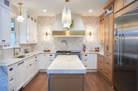 White kitchen with marble counters, gold pendants and stainless refrigerator