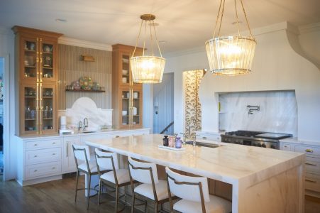 White kitchen with marble waterfall island, gold pendant lights and bar seating