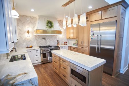 White kitchen with marble waterfall island and custom wood hood