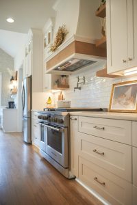 White kitchen with custom wood range hood and stainless range
