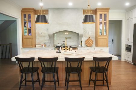 Wood kitchen with white island, blue range hood and black bar stools